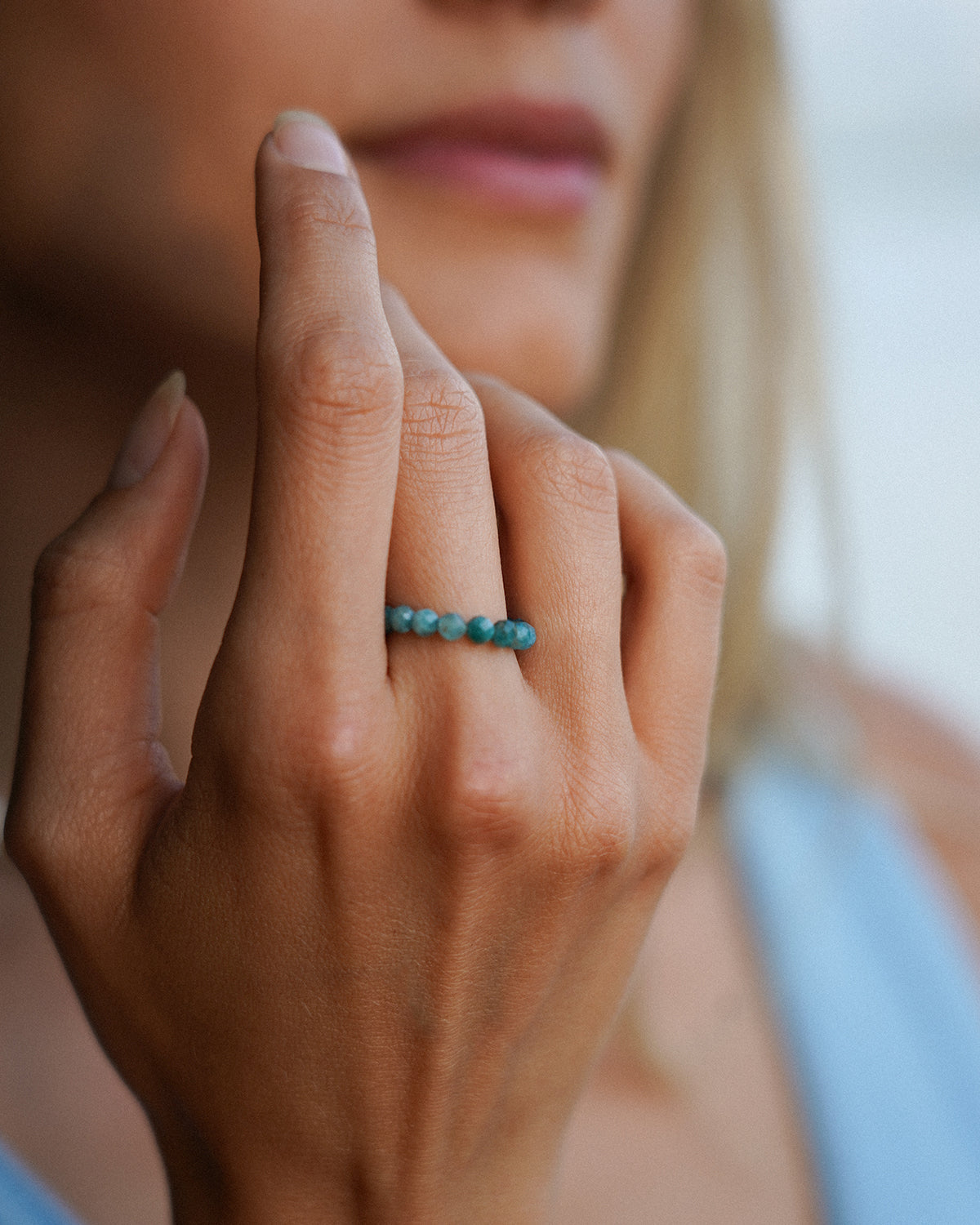 Edelstein Ring für Damen mit kleinen facettierten blau-türkisen Natursteinen am Finger getragen, minimalistischer Schmuck im Close-up.
