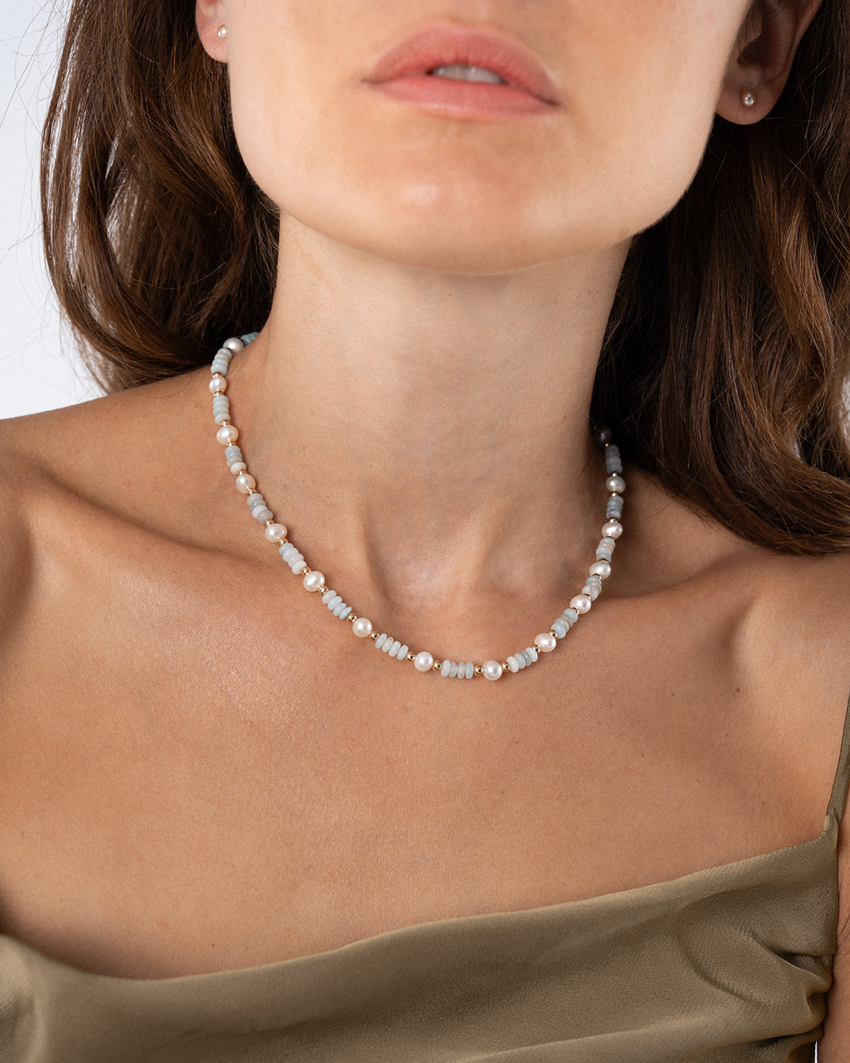Detailaufnahme einer Halskette für Damen mit Süßwasserperlen, hellblauen Edelsteinperlen und goldenen Akzenten am Hals einer Frau – elegante Perlenkette im natürlichen Slow-Living-Stil.