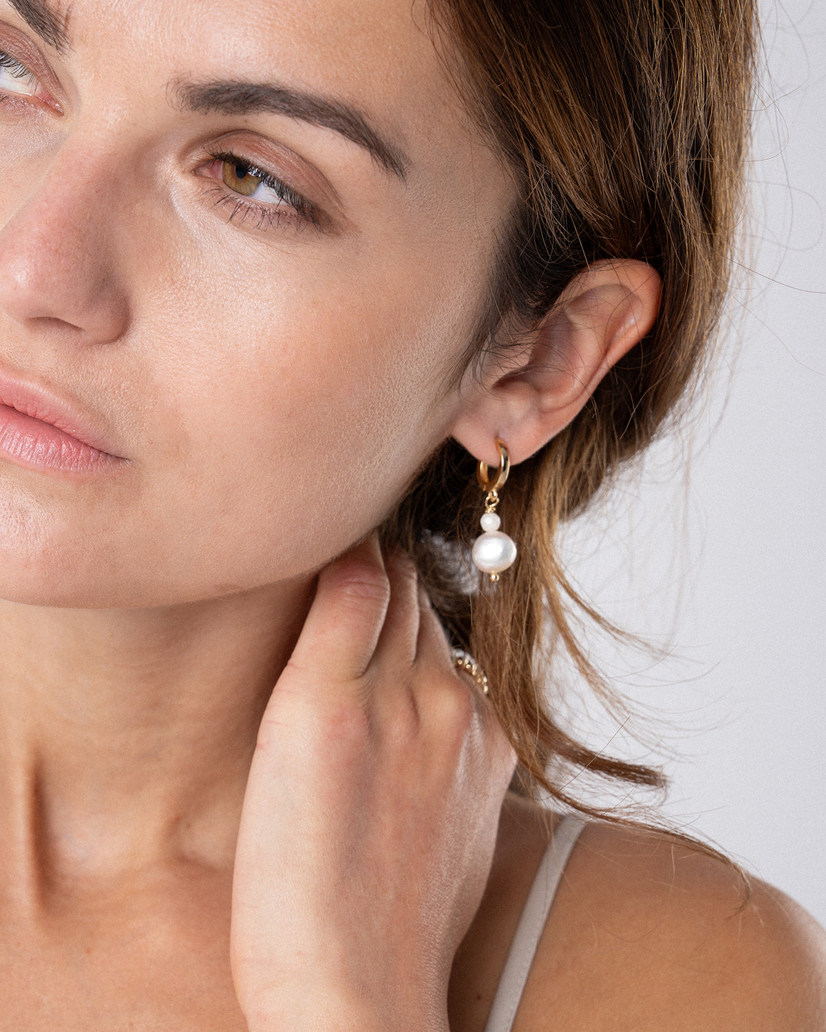 Nahaufnahme einer Frau mit goldenen Creolen Perlenohrringen mit Süßwasserperle – elegante Damen Perlenohrringe im minimalistischen Design.